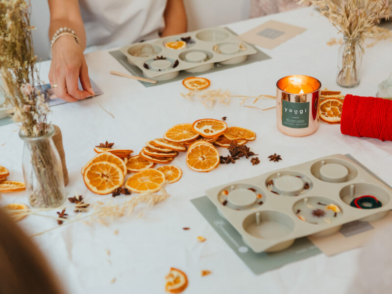 Soy candle-making materials and dried oranges segments on a table